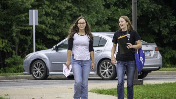 A couple of women walking on a sidewalk